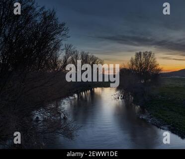 Impressive sunset over the Manzanares river with the vegetation on the shore and the sunset lights reflected in its waters Stock Photo