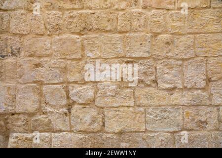 deteriorated, textured, aged, golden yellow brick-shaped stone wall Stock Photo