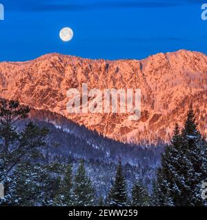 full moon setting over the bridger mountains in winter near bozeman, montana Stock Photo