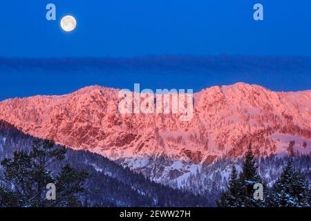 full moon setting over the bridger mountains in winter near bozeman, montana Stock Photo