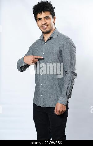 Young man's gray formal shirt mockup front-gray shirt template on white background-Hispanic young man pointing at his shirt smiling on white backgroun Stock Photo