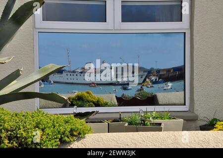 Sciillonian 3 reflected in the window of a cottage on the Strand in Hugh Town, St Mary's, Isles of Scilly. Stock Photo