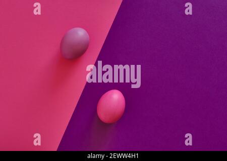Abstract combined violet-pink background with diagonal. Painted violet egg on a pink background, painted pink egg on a violet background. Top view. Ea Stock Photo
