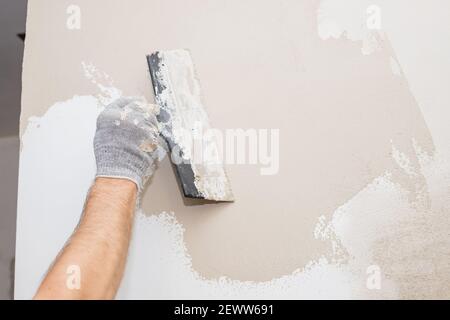 hand of builder worker plastering at wall.Renovation workers hand plastering the wall.Construction finishing works.work aligns with a spatula wall Stock Photo