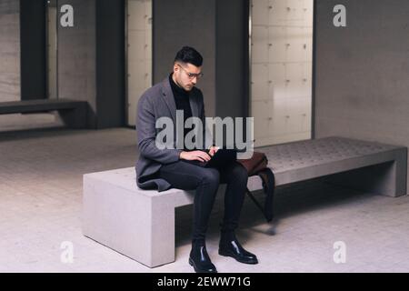 Businessman sitting on a bench typing on his laptop. Stock Photo