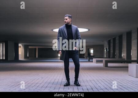 Handsome businessman standing with laptop with hands in pockets. Stock Photo