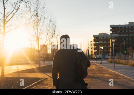 Backlight of a businessman walking down the street at sunset. Stock Photo