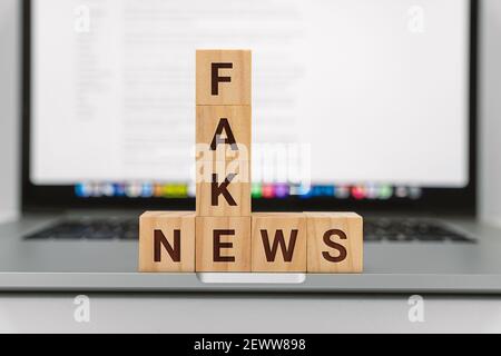 Fake News on Wooden Block Against Laptop Screen Stock Photo