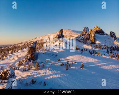 Colorful winter sunset in Sheregesh ski resort mountains with clouds. Aerial top view forest Russia. Stock Photo