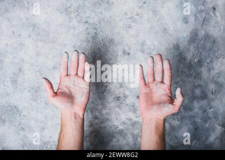 Man hands covered with paint on gray concrete wall background Stock Photo