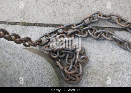 Length of steel chains attached to a concrete post Stock Photo