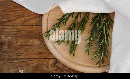 Sprigs of rosemary on a wooden board for cutting. Rustic style. Spice Stock Photo