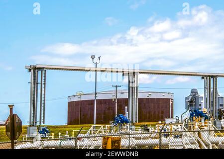 Rusty oil tank at tank farm in Cushing Oklahoma with valves and pipes and overhead rail at pipeline loading facility where most of USA WTI crude is st Stock Photo