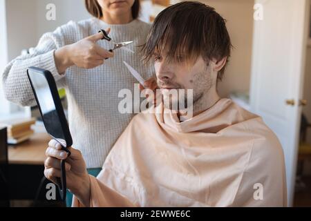 Home haircut. Man cutting hair at home. Life in pandemic during lockdown. How to cut your own Hair when hairdressers are closed. Easiest Self-haircut Stock Photo