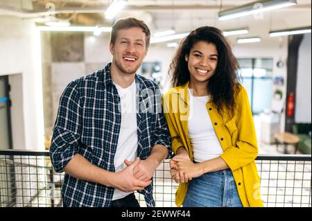 Portrait of business coworkers or student friends. Handsome caucasian man and beautiful african american woman work or study together, colleagues look at the camera, smiling Stock Photo