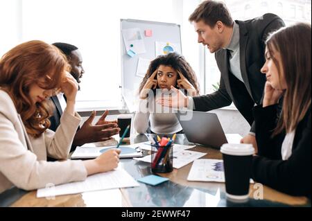 Focused colleagues in formal wear at negotiations. Multiracial male and female employees discussing about ideas for project, learning financial graphs. Business partners brainstorming together Stock Photo