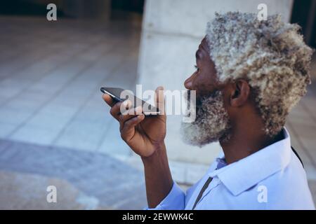 African american senior man standing in street talking on smartphone Stock Photo