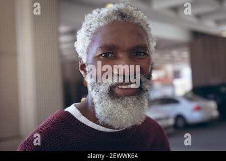 Portrait of casually dressed african american senior man with beard smiling in street Stock Photo
