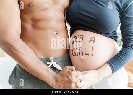 Crop ethnic man and pregnant woman hugging at home Stock Photo