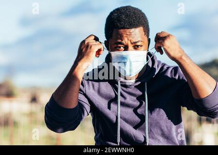 Portrait of an Afro-American boy putting on a face mask. Stock Photo