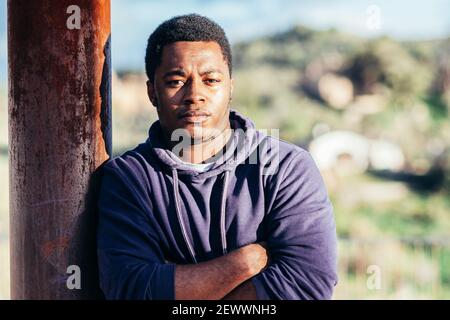 Portrait of an African American boy wearing a purple sweatshirt in an urban space. Stock Photo