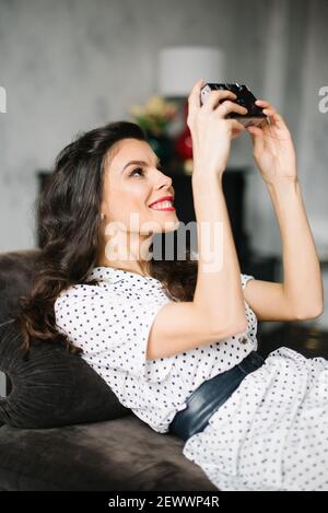 Young woman in retro style dress with analog camera making a selfie Stock Photo