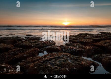 Sun setting over tide pools in the Pacific Ocean Stock Photo