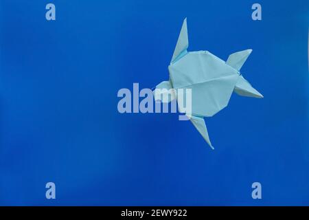 Origami paper turtle from above against blue background with copy space Stock Photo
