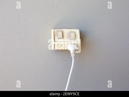 Outdoor Clipsal double socket with a plug and cord plugged into one outlet Stock Photo