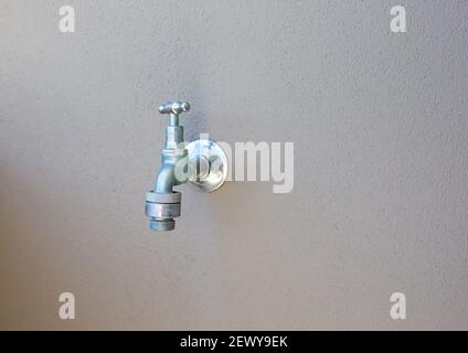 Outdoor tap with hose connection against a plain rendered wall Stock Photo