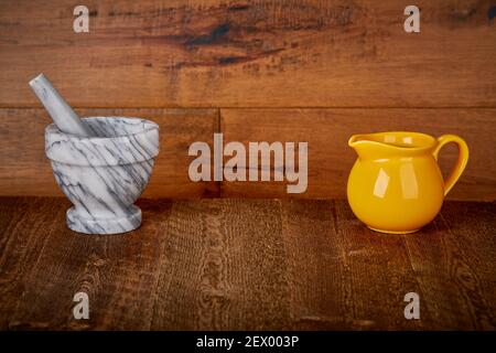 Small Yellow Ceramic pitcher pouring Jug and Marble Stone mortar and pestle grinder crusher on Old Barn wood floor and wall Background Shooting Surfac Stock Photo
