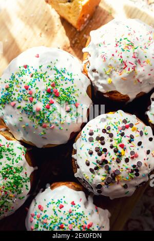 Many Traditional eastern europe Russian and ukrainian Easter cake kulich decorated with sweet sugar icing on wooden table morning sunlight ray. Tasty Stock Photo