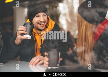 Young loving couple drinking coffee in a cafe behind the glass Stock Photo