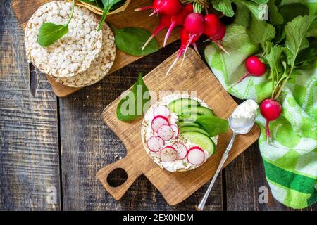 Healthy breakfast. Crunchy crispbread Sandwiches with ricotta, radish and fresh cucumber on a wooden table. Top view flat lay. Copy space. Stock Photo