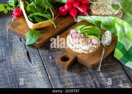Healthy breakfast. Crunchy crispbread Sandwiches with ricotta, radish and fresh cucumber on a wooden table. Copy space. Stock Photo