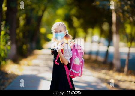 School Girl wearing mask and backpack to protect from coronavirus. Child going school after pandemic over. Stock Photo