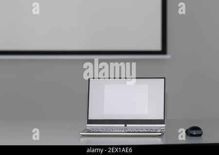 a laptop is on a table in front of a presentation screen Stock Photo
