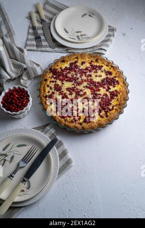 Curd tart with red lingonberries. Open round pie with berries on a white table. Baking food. Stock Photo