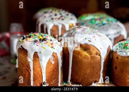 Many Traditional eastern europe Russian and ukrainian Easter cake kulich decorated with sweet sugar icing on wooden table morning sunlight ray. Tasty Stock Photo