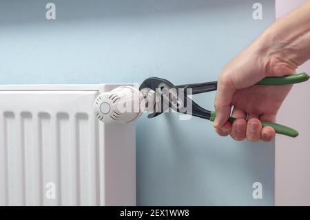 Plumber Fixing Radiator With Wrench. Heating radiator with temperature regulator, thermostat. Stock Photo