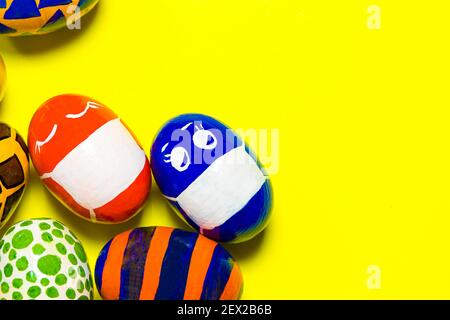 Colored colored eggs on a yellow background. Two eggs in a mask due to the quarantine of the covid-19 coronavirus. With a place for text copy space Stock Photo