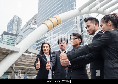 Group of multiethnic business team confident standing and showing thumbs up in the city Stock Photo
