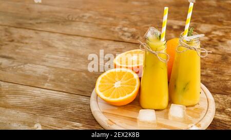 Orange juice on a wooden tray. Sliced orange and ice cubes. Snack at the resort, coolness on a hot summer day. Stock Photo