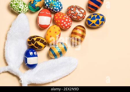 Easter banner with painted eggs, rabbit ears on a light beige minimalist background with copy space for text. Stock Photo