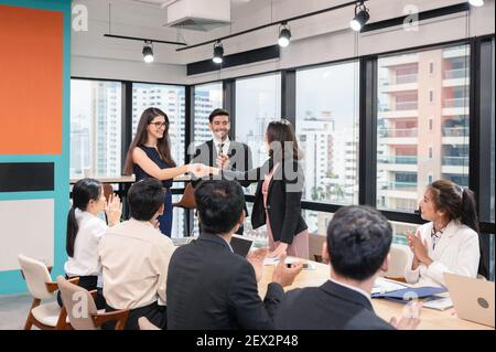 Multi ethnic businesswoman shaking hands cooperation for corporate agreement with coworkers in modern office Stock Photo