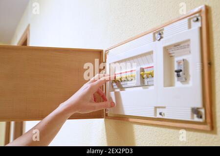 Woman hand turning off fuse box in the house. Selective focus. Stock Photo
