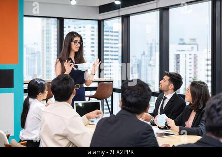 Caucasian executive proposes company policy on wearing face mask in corporate during meeting. New normal office. While pandemic of Coronavirus Stock Photo
