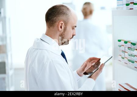 pharmacist scrolling on digital tablet checking medication . Stock Photo