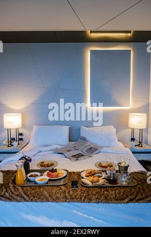 Breakfast in bed in room, breakfast with coffee news and croisant in bedroom, Breakfast in bed with orange fruits and pastries on a tray.  Stock Photo