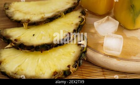 Fresh pineapple slices and and ice cubes on a wooden background. Fresh pineapple juice on the background. Cool on a hot summer day. Snack at resort Stock Photo